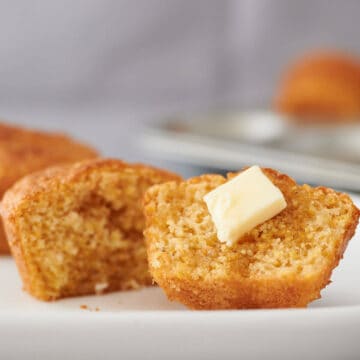 close up of corn muffin cut in half with butter